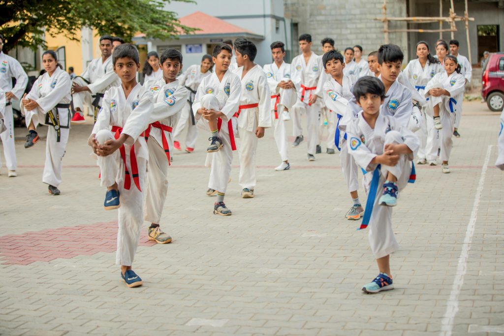 Children practicing Taekwondo martial arts outdoors, focusing on balance and discipline.